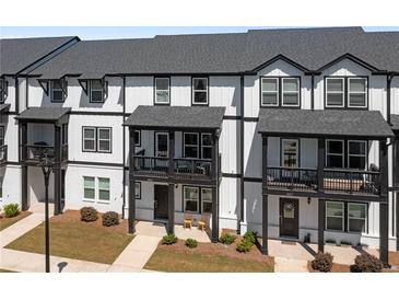 Charming townhome exterior showcases a modern black-and-white design with inviting front porches and landscaped yard at 823 Mackay Crk, Woodstock, GA 30188