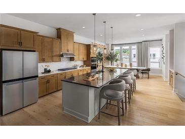 Open concept kitchen with stainless steel appliances, large island with seating and an adjoining dining area at 1492 Wicker Wood Se Pl # 24, Smyrna, GA 30080