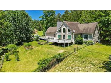 Charming home featuring a large deck, yard and mature trees on a sunny day at 3909 Laurens Ln, Snellville, GA 30039