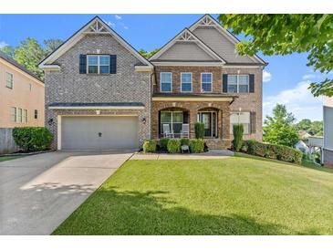 Charming two-story brick home with a well-manicured lawn and inviting front porch at 4022 Roberts Crest Dr, Suwanee, GA 30024