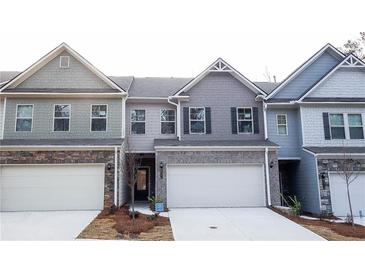Attractive townhome featuring a well-manicured lawn, a two car garage, and stone accents at 2304 Shetley Creek Dr, Norcross, GA 30071