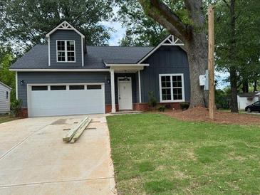 Charming home featuring a well-maintained lawn, and a paved driveway leading to an attached garage at 325 Garrison Se Dr, Marietta, GA 30060