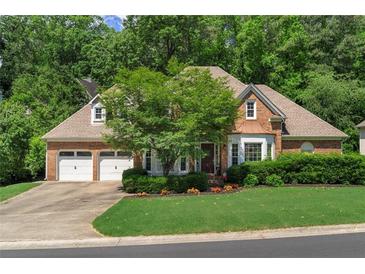 Charming brick home featuring a two-car garage, well-manicured lawn, and lush landscaping at 4381 Laurian Nw Dr, Kennesaw, GA 30144