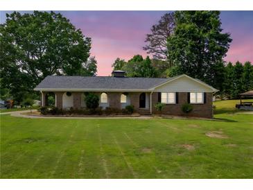 Charming brick home with manicured lawn and lovely curb appeal, complemented by mature trees and an inviting facade at 3642 S Bogan Rd, Buford, GA 30519