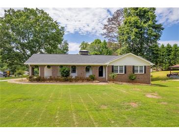 Charming brick home featuring a well-manicured lawn and a welcoming front porch with beautiful trees at 3642 S Bogan Rd, Buford, GA 30519