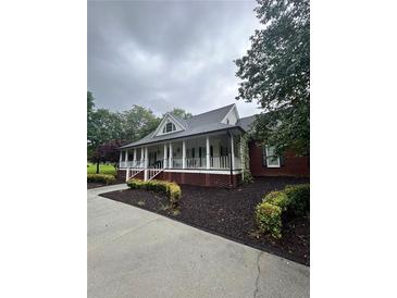 Charming brick home with a welcoming covered front porch, black shutters, and manicured landscaping at 3677 Malachi Way Way, Loganville, GA 30052