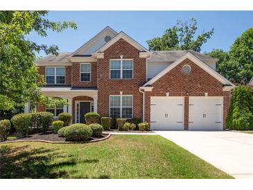 Traditional brick two-story home featuring a manicured lawn, an attached two-car garage and mature trees at 130 Bevington Ln, Woodstock, GA 30188