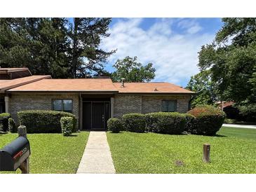 Charming single story home with a brick facade, manicured lawn, and mature trees at 5526 Stoneleigh Ct, Stone Mountain, GA 30088