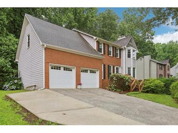 Charming two-story home with a brick facade, two-car garage, and a well-manicured front yard, complemented by lush greenery at 1369 Willowbrook Sw Dr, Marietta, GA 30064