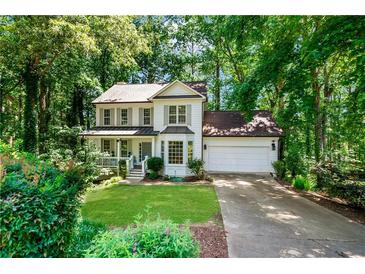 Charming two-story home with a well-manicured front yard and a two-car garage, surrounded by lush greenery at 404 Summerchase Way, Woodstock, GA 30189