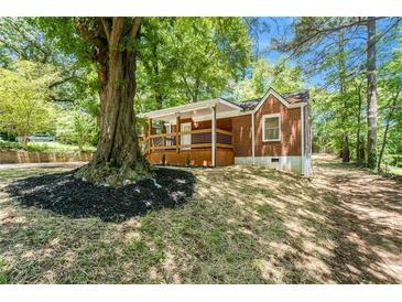 Charming brick home featuring a cozy front porch and beautiful landscaping around a mature tree at 2174 Rexford Dr, Decatur, GA 30034