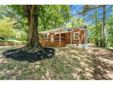 Charming brick home with a welcoming front porch, complemented by lush landscaping and a mature tree in a serene setting at 2174 Rexford Dr, Decatur, GA 30034