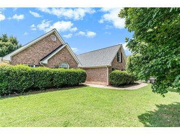 Brick home featuring mature landscaping, a symmetrical design, and a well-maintained lawn at 1478 Elena Dr, Mcdonough, GA 30253