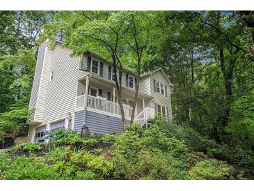 Charming two-story home with a covered front porch nestled among mature trees and lush landscaping at 507 Spring Creek Ne Way, Marietta, GA 30068