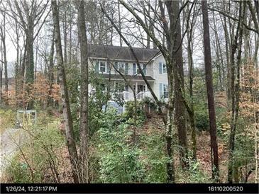 Two-story home with light blue shutters, surrounded by mature trees and lush greenery, offering a serene setting at 507 Spring Creek Ne Way, Marietta, GA 30068