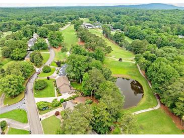 Expansive aerial view of a lush golf course community with mature trees and a tranquil pond at 12162 Mountain Laurel Dr, Roswell, GA 30075