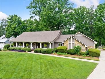 Charming single-story home with a welcoming front porch and beautifully landscaped front yard and stone accents at 12162 Mountain Laurel Dr, Roswell, GA 30075