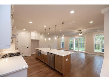Modern kitchen with an island, stainless steel appliances, and hardwood floors leading to a room with sliding glass doors at 512 Winston Croft Cir # 56, Johns Creek, GA 30022