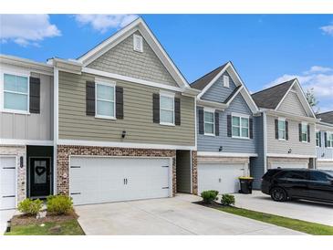 View of townhome exteriors, showcasing brick accents, garages, and well-maintained landscaping at 11730 Chatham Dr, Hampton, GA 30228