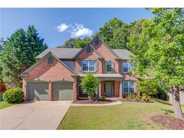 Charming brick two-story home with a three-car garage and well-manicured lawn at 5115 Amberden Hall Dr, Suwanee, GA 30024