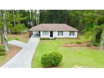 Charming exterior of a white home, surrounded by lush landscaping and a long driveway at 537 Eastside Dr, Dacula, GA 30019
