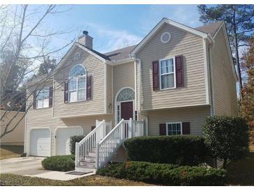 Two-story home featuring neutral siding, complementary shutters, well-maintained landscaping, and an attached two-car garage at 5709 Newnan Cir, Austell, GA 30106