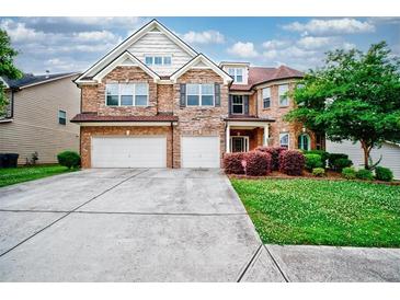 Beautiful two-story brick home with a two-car garage, landscaped front yard, and inviting entrance at 3740 Lake Enclave Way, Atlanta, GA 30349