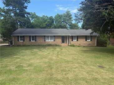 Charming brick ranch home features a well-manicured lawn and mature trees at 2266 Eastgate Dr, Snellville, GA 30078