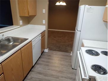 Galley kitchen featuring wooden cabinets, laminate countertops, and white appliances at 8202 Fairington Village Dr, Lithonia, GA 30038