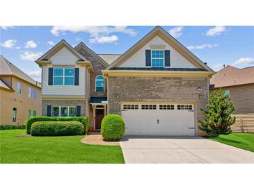 Charming two-story home featuring a brick facade, attached two-car garage, lush lawn, and manicured hedges at 2185 Creole Cir, Cumming, GA 30040