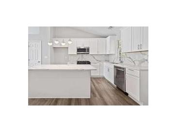 Bright kitchen features white cabinetry, stainless steel appliances, an island and marble countertops at 5950 Milligan Ct, Atlanta, GA 30349