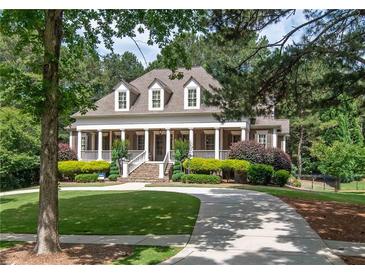 Stunning two-story home with a grand front porch, manicured lawn, and a circular driveway nestled amongst mature trees at 100 Trotters Ridge, Fayetteville, GA 30215
