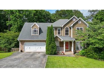 Charming two-story home featuring a stone and vinyl facade, two-car garage, and well-manicured lawn at 2004 Spicers Ln, Woodstock, GA 30189