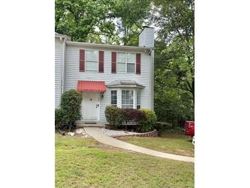 Charming two-story townhome with red awnings, manicured landscaping, and a stone walkway leading to the front door at 1104 Huntington Se Trce, Smyrna, GA 30082