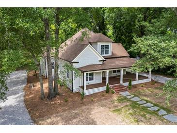 Charming home with covered porch, stone walkway, beautiful landscaping, and mature shade trees at 159 S Forest S Ave, Social Circle, GA 30025