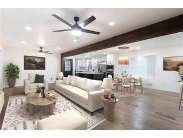 Inviting living room with modern ceiling fan, stylish furniture, and open layout to the kitchen and dining area at 1582 Pine Cir, Austell, GA 30168