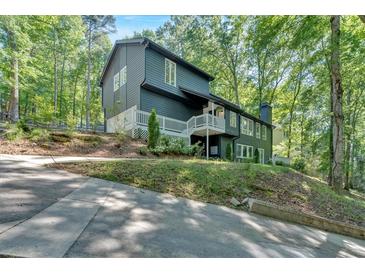 Two-story home with dark siding, white trim, and a charming balcony nestled amongst mature trees at 510 Watergate Ct, Roswell, GA 30076