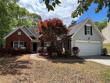 Charming home with a brick and vinyl exterior, complemented by a well-manicured lawn and mature landscaping at 1221 St James Pl, Loganville, GA 30052