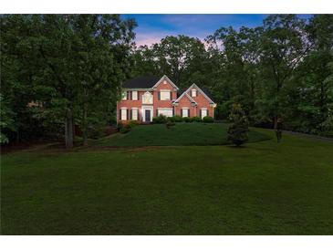 Traditional brick home with a manicured lawn and mature trees at dusk at 9048 River Bend Ct, Villa Rica, GA 30180