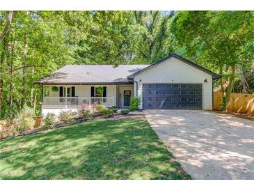 Charming single-story home features a well-kept lawn, covered porch, and two-car garage nestled among mature trees at 2020 Commonwealth Pl, Cumming, GA 30041