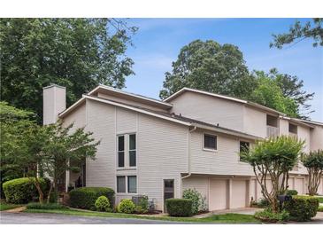 A charming townhouse featuring neutral siding, attached garages, and a well-manicured lawn with mature trees at 4096 Audubon Dr, Marietta, GA 30068