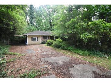 Quaint one-story home nestled among lush trees with a covered carport and driveway at 1847 Colt Dr, Brookhaven, GA 30341