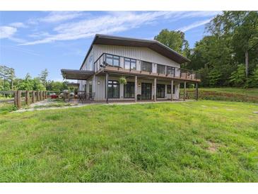 Expansive, modern farmhouse with a deck overlooking a large manicured lawn and wooded acreage at 1971 Centennial Rd, Rutledge, GA 30663