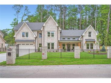 Stunning brick home with black iron fence and manicured lawn, surrounded by mature trees at 2625 Beverly Ln, Snellville, GA 30078