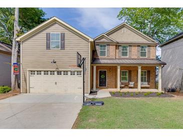 Charming two-story home with a covered front porch, a two-car garage, and a well-manicured lawn at 440 S Alexander St, Buford, GA 30518