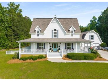 Charming two-story white home with a welcoming front porch and well-manicured landscaping at 692 Brooks Woolsey Rd, Brooks, GA 30205