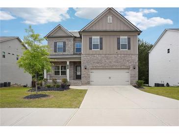 Charming two-story home featuring a brick and siding exterior with a well-manicured front yard and a two-car garage at 106 Logan Pass Dr, Loganville, GA 30052