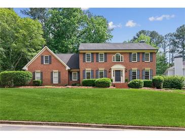 Beautiful two-story brick home with a manicured green lawn and mature trees at 6165 Pin Oak Ln, Alpharetta, GA 30005