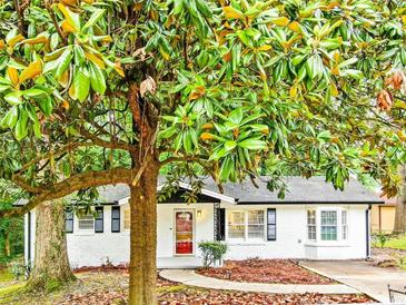 Charming white brick home featuring a well-manicured lawn, inviting walkway, and mature magnolia tree at 4808 Oak Ct, Ellenwood, GA 30294