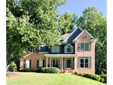 Charming two-story brick home with a lush front yard, mature trees, and a welcoming facade at 2073 Woodside Park Dr, Woodstock, GA 30188
